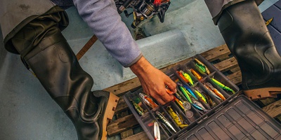 A person grabs a lure from a gear box