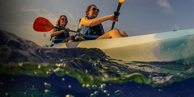 Two young women smiling in blue kayak wth sunglasses