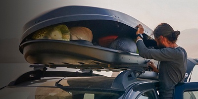 A person opens their rooftop storage box