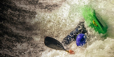 A kayaker turning over in whitewater