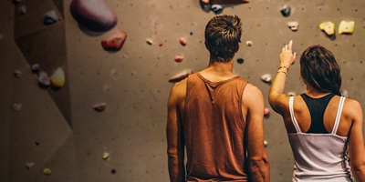 A woman points out a route to a man on an indoor climbing wall