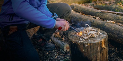 Girl making fire by flint outdoors