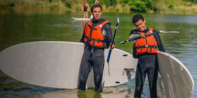 Two men look on before stand-up paddle boarding