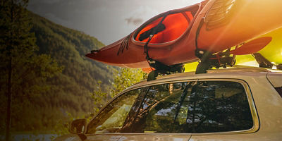 A kayak sits on top of a car on a rack