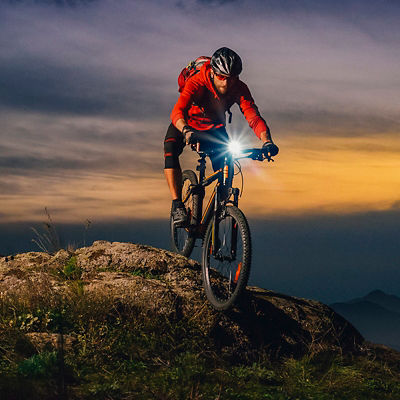 A man rides his mountain bike at dusk with a bike light