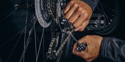 A man uses a hex tool to adjust bicycle derailleur gear cable