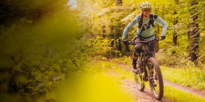 A female mountain biker riding her e-MTB on a variety of trails.