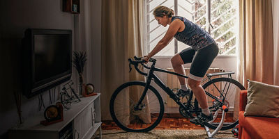 A woman is training on the bike with a smart trainer at home.