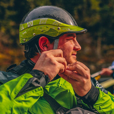 A man in a drysuit puts on a helmet before going whitewater rafting on the Lochsa River in Idaho. 