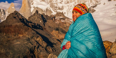 A woman wrapped in a sleeping bag in the mountains