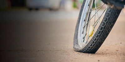 The rear wheel of the bicycle is flat and is left parked on the sidewalk to change and fix it.