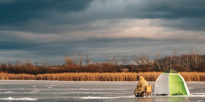 A person ice fishing with a tent
