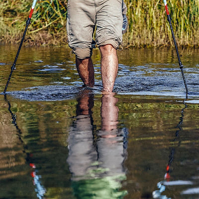 A person crosses a river with poles