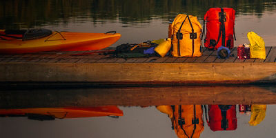 Kayak and canoe packs on dock with reflection Algonquin Park Ontario Canada