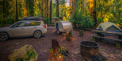 A car campsite with teardrop trailer and tent  in the forest
