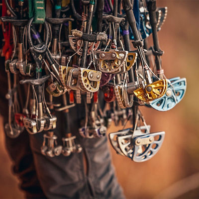 An assortment of trad climbing gear hangs from a climbers harness.