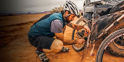 Mountain biker uses brush to clean the dust off the chain of his bike.
