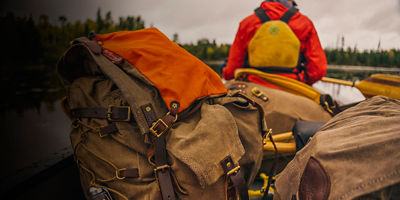 A woman paddles a Wenonah canoe full of traditional canoe packs on Jack Lake in the BWCAW.