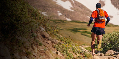 A man runs a trail with a running pack 