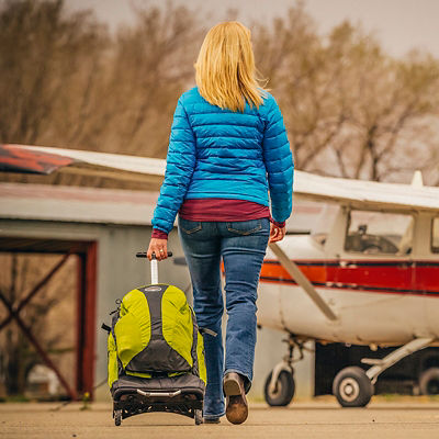 A woman takes her luggage to a plane in a small, local  airport 