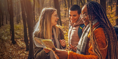 Three women look at a map in the forest