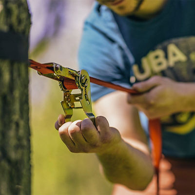 Setting up slacklining equipment and tightening the line on a tree