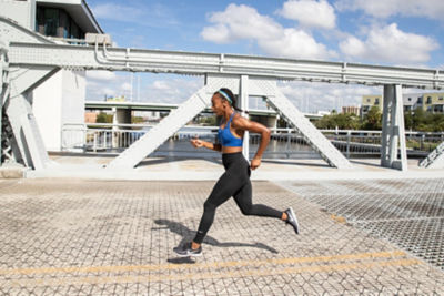 Woman running across bridge in blue tank top