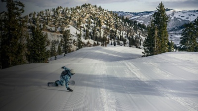 A man snowboards down the slopes with a small pack on