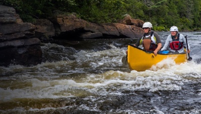 A group of people paddling in whitewater with a canoe