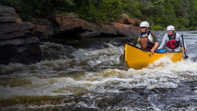 A group of people paddling in whitewater with a canoe