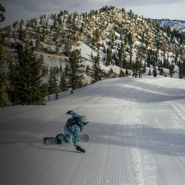A man snowboards down the slopes with a small pack on