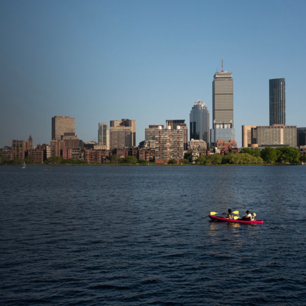 Two people kayak with the boston skyline