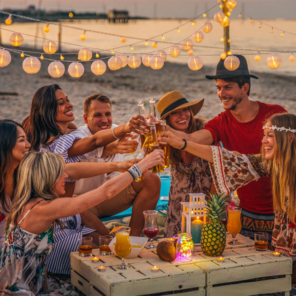 Group of friends under lights having a celebration at the beach