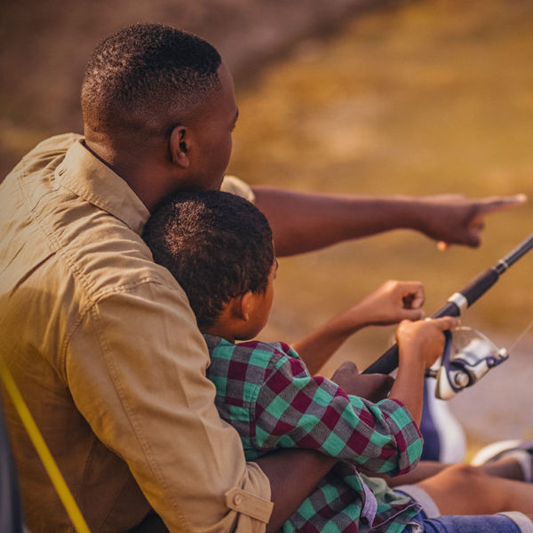 Father and son fishing together in park