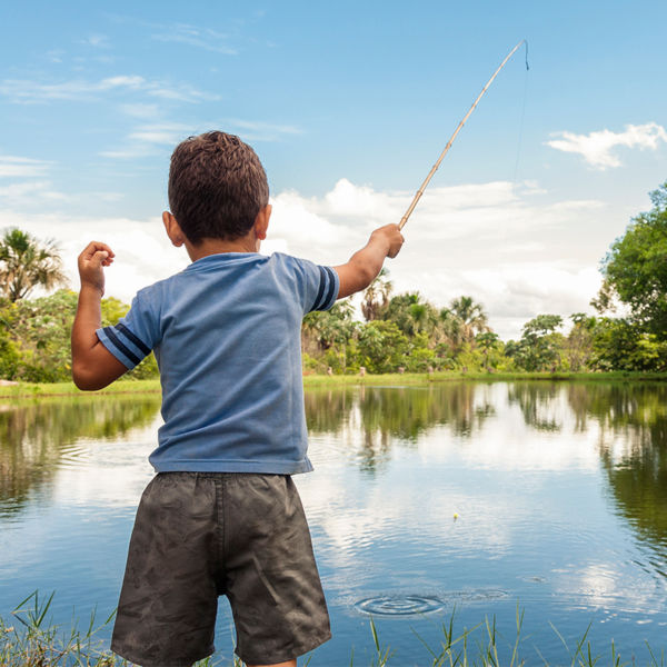 Kid learning how to fish, holding a rod on a lake