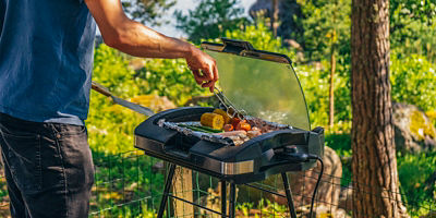 Man preparing food on summer day with electric grill