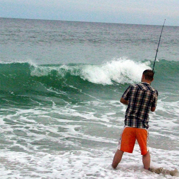 A person surf casts from the beach
