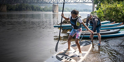 A girl stands up on a paddle board as part of First Waves
