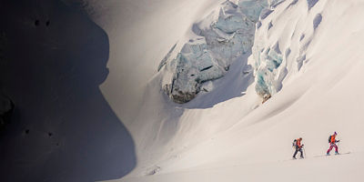 Backountry women skiers skinning up hill in the dramatic snowy mountains of the rugged Selkirks in British Columbia.