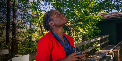 Nicole Jackson looks up for birds holding binoculars while birdwatching