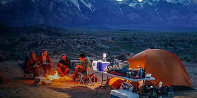 Four people sit around a camp fire and eat dinner at the Alabama Hills near Lone Pine, California.