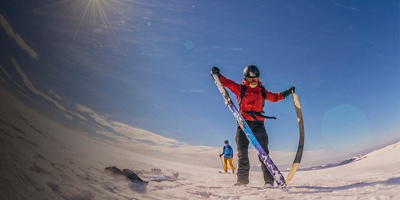 A person pulls off skins during ski touring on sunny day