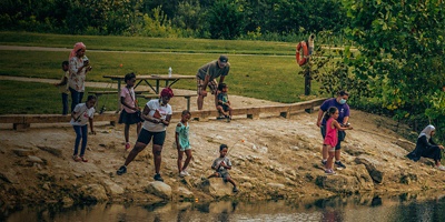 Children and parents fish along the water during YMCA Outdoor Inclusive Adventures event