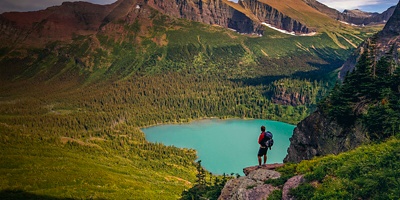 Silhouette of a man standing on a ridge looking over Lower Grinnell Lake in Glacier National Park, Montana