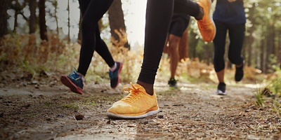  A group of four young adults trail running in forest