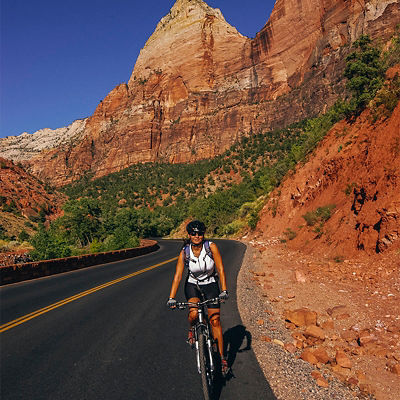 A woman cycling on a road in Zion National Park