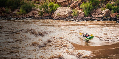 A man surfs a wave at 24 Mile Rapid (Georgie Rapid) on the Colorado River, Grand Canyon National Park, Arizona, USA.