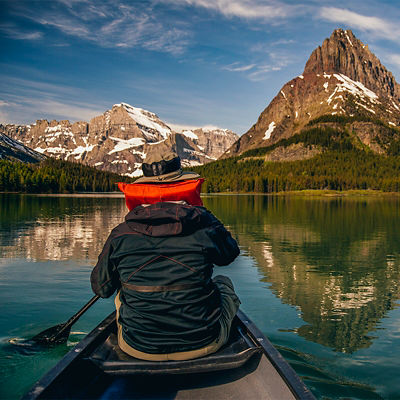 A person paddles on Swiftcurrent Lake during sunrise in Montana