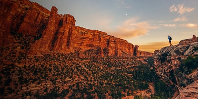 A hiker stands on the edge of a clif at Bears Ears