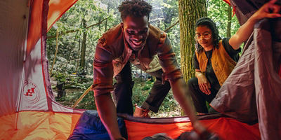 Two explorers setting up sleeping bags in a tent